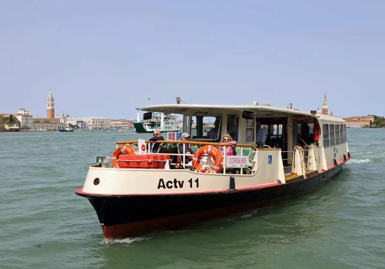 Battello Actv 11 naviga tra le acque di Venezia, con lo skyline di Chioggia sullo sfondo.