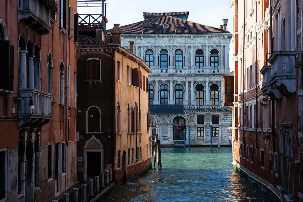 Un canale a Venezia, con palazzi storici che si affacciano sull'acqua. Un'atmosfera da ca' Pesaro, con la luce che gioca sulle facciate.