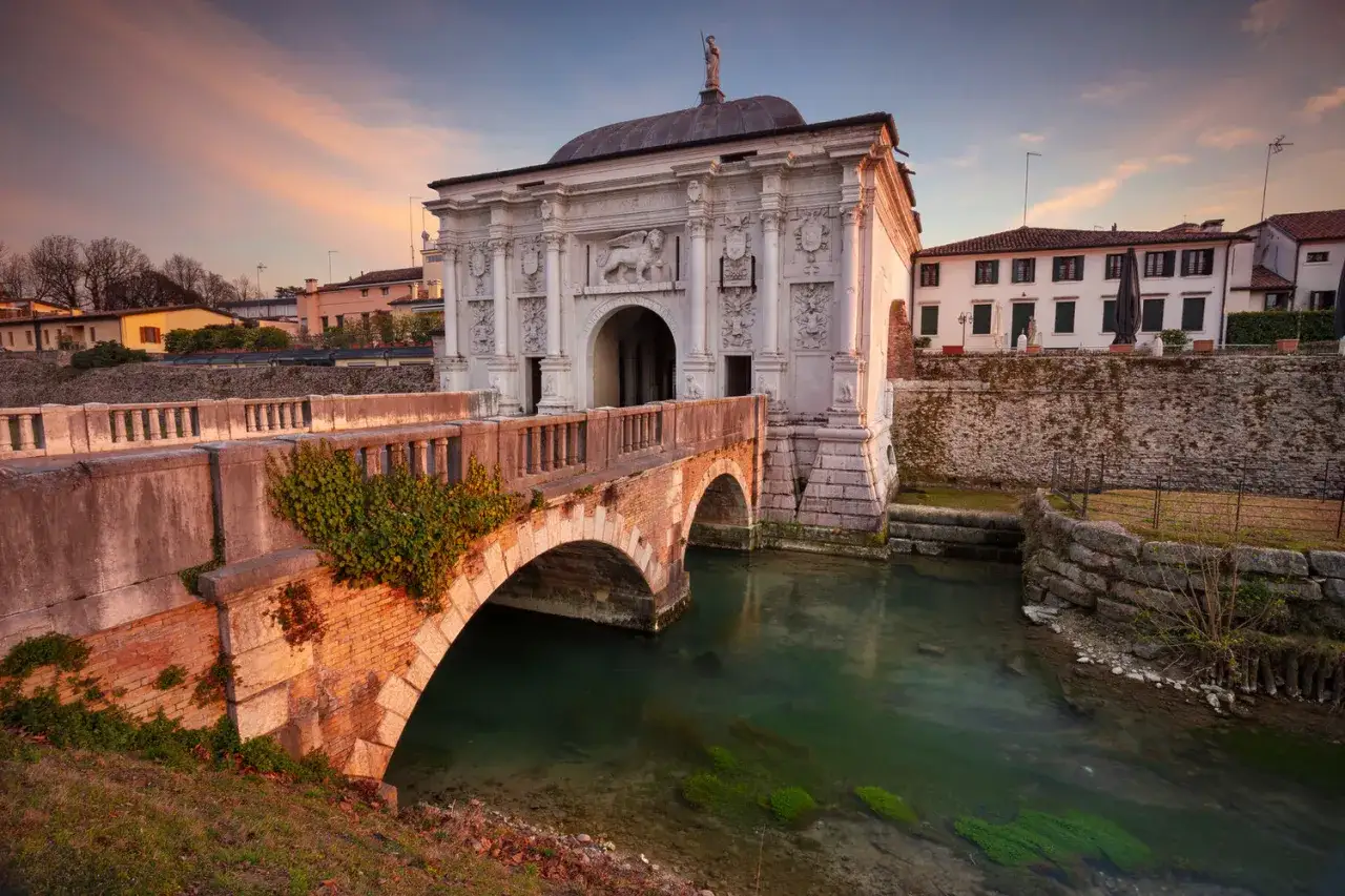 Porta San Tomaso a Treviso, un'idea per cosa fare a Treviso nel weekend. Un ponte in mattoni attraversa un canale con acqua verde.