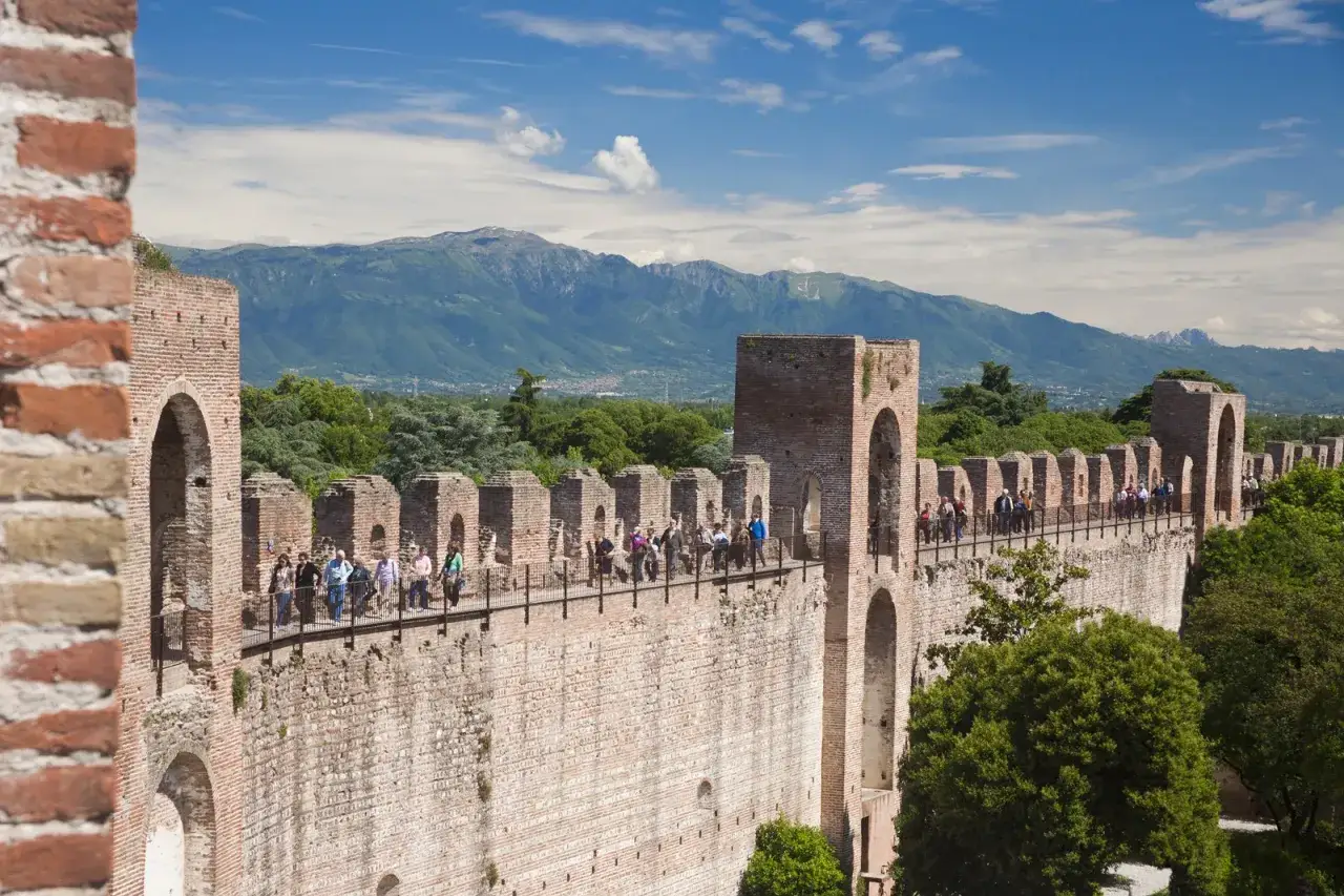 Passeggiata sulle mura della cittadella di Padova, con turisti che ammirano il panorama montuoso.