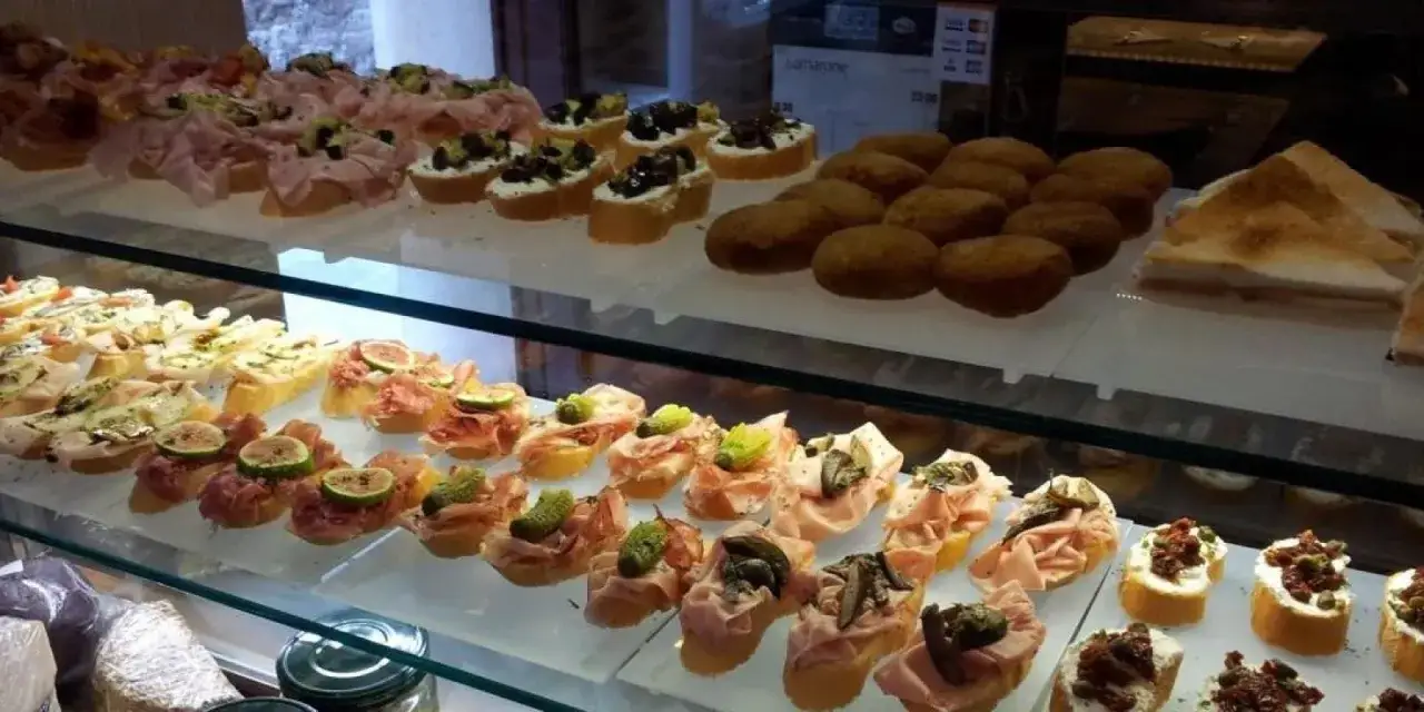 Esposizione di migliori cicchetti Venezia: crostini con affettati, fichi, olive e verdure, fritti e tramezzini.