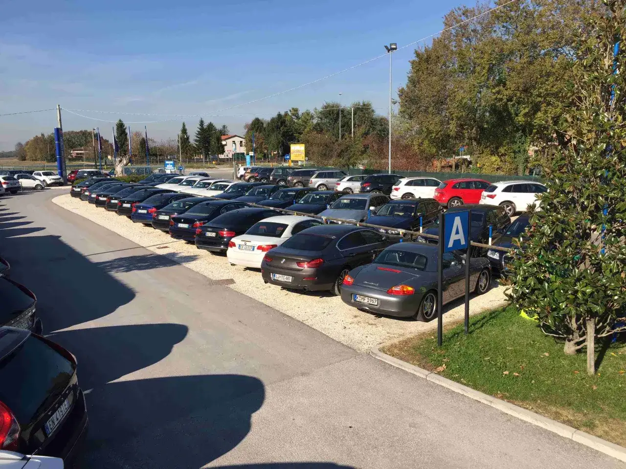 Parcheggio con auto di varie marche, forse vicino a Venezia Mestre o Santa Lucia. Un cartello blu con la lettera