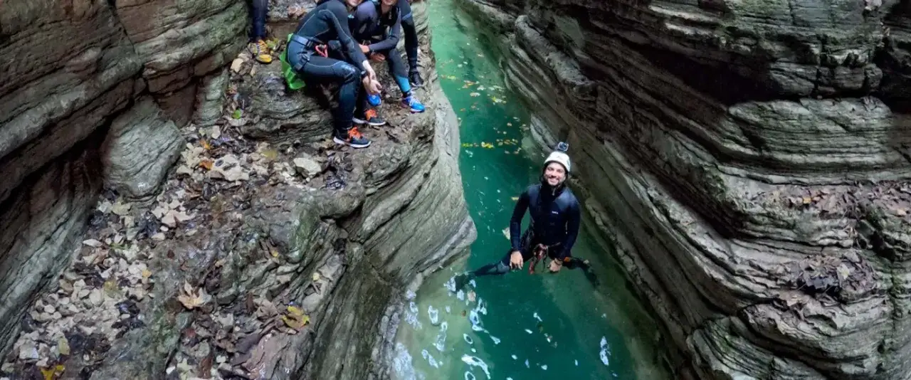 Avventura di canyoning nelle Dolomiti: un gruppo di amici si prepara a scendere in un torrente cristallino tra pareti rocciose imponenti.